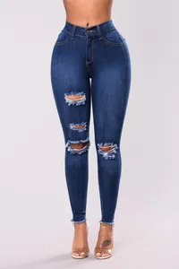 Detalle de jeans skinny azules de tiro alto con rotos en las rodillas y bajos deshilachados.