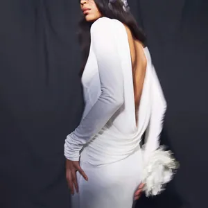 Détail d'une robe blanche à manches longues avec un dos nu drapé et une taille froncée