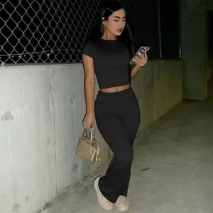 Full view of black two-piece set with crop top and flared leggings on model in street setting.