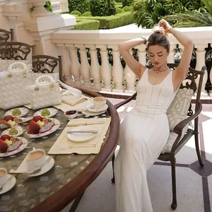 Elegant white sleeveless backless knit long dress in a luxury outdoor setting