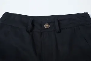 Detaillierte Nahaufnahme von Bund, Gürtelschlaufen und Metallknopf einer schwarzen Cargo-Hose.