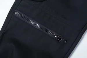 Detailansicht einer schwarzen Cargohose mit einem robusten Metallreißverschluss.