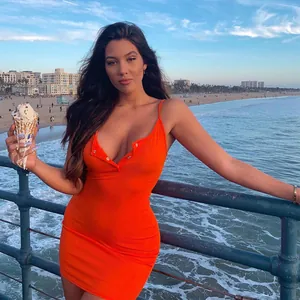 Sexy orange ribbed bodycon camisole dress worn by a model at the beach pier setting