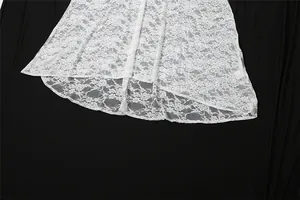 Close-up detail of the intricate white floral lace fabric and hemline of an elegant maxi dress
