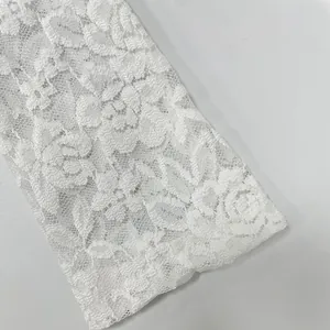 Close-up detail of white floral lace fabric showing intricate patterns on dress sleeve