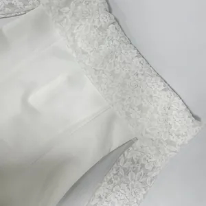 Close-up of elegant white dress showing intricate floral lace detail on off-shoulder neckline