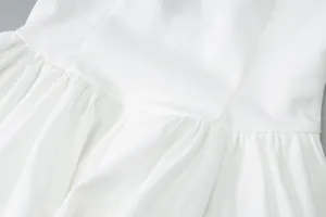 Close-up detail showing the pleated waist and fabric texture of a French white dress.