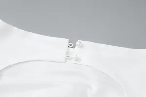 Detailed view of elegant pearl button closure on the back of a white French style dress