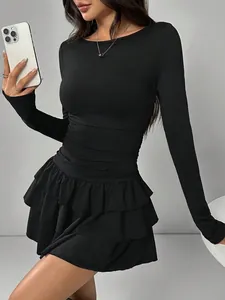 Detail of black long-sleeved dress featuring waist ruching and ruffled hem.