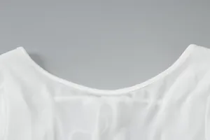 Close-up detail of the U-neckline and sheer fabric texture on a white summer dress