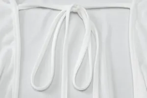 Detailed macro view of a white dress featuring an elegant tie-back hollow design.