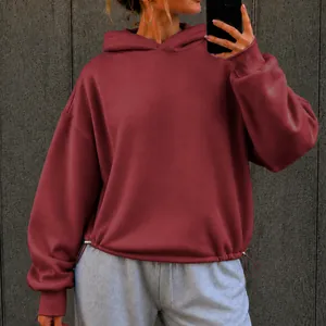 Close-up of a burgundy oversized hoodie with adjustable drawstring hem for a casual fit.