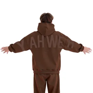 Détail d'un sweat à capuche marron oversize avec lettrage YAHWEH en relief sur le dos