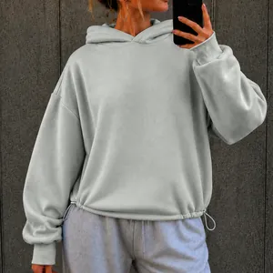 Close-up of oversized light grey hoodie featuring a drawstring hem and relaxed fit.