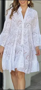 Détail de la robe blanche à col en V avec broderie anglaise complexe et motifs dentelle.