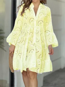 Détail d'une robe jaune à col en V avec broderie anglaise et manches cloche