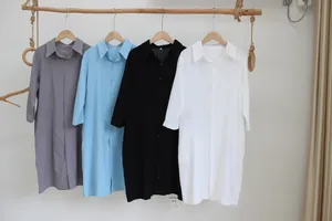 Vari colori di abiti a camicia in cotone e lino appesi a una rastrelliera di legno rustica