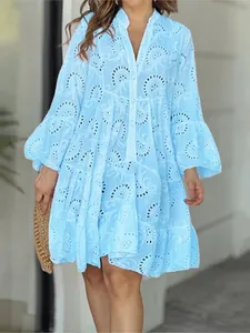 Vue détaillée d'une robe bleue à col en V avec des motifs de broderie anglaise complexes.