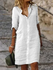 Detail view of a white linen button-down shirt dress with rolled-up sleeves.