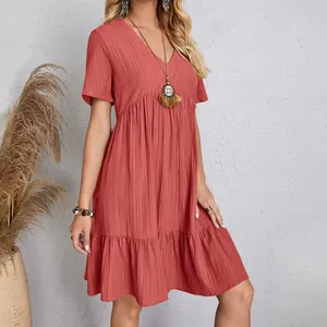 Detail of a terracotta textured fabric summer dress with tiered hem and V-neck line.