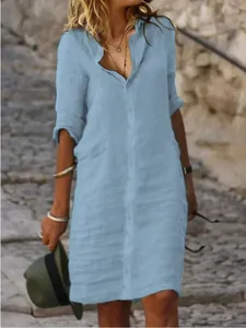 Detail of light blue linen shirt dress with button-down collar and relaxed fit.