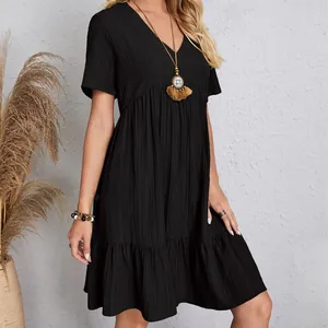 Close-up view of a casual black short-sleeved V-neck tiered flowy dress worn by a model