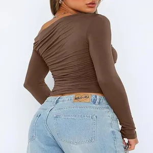 Detail of brown asymmetrical off-the-shoulder long sleeve top with ruched texture