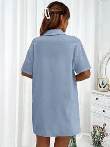 Vista trasera de camisa de manga corta azul claro en un entorno interior suave
