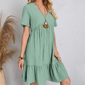 Detail view of a sage green tiered dress with textured fabric and V-neckline.