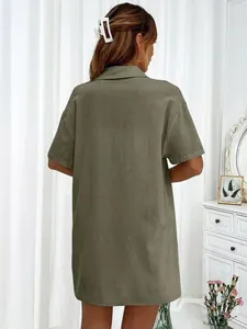 Back view of a casual olive green short-sleeved shirt on a model in a cozy room