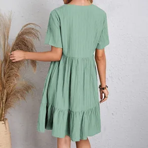 Detailed back view of a sage green textured short-sleeved flowy tiered mini dress.