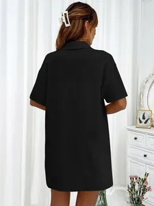 Vista posterior de una camisa negra holgada de manga corta en un entorno doméstico.