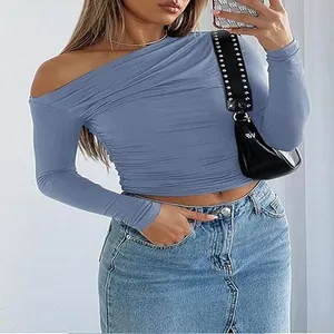 Close-up of blue off-shoulder crop top paired with denim skirt and black handbag