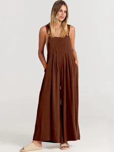 Modelo con mono holgado de algodón y lino marrón con perneras anchas y bolsillos en estudio.