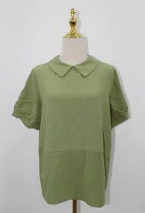 Detailed front view of a loose light green cotton short-sleeved blouse with a Peter Pan collar