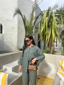 Détail de femme portant un ensemble deux pièces en lin vert olive dans un patio ensoleillé