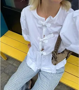 Detail shot of a white puff sleeve blouse with front bow ties on a fashion model.