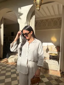 Détail d'un ensemble 2 pièces en lin beige porté par un mannequin dans une villa ensoleillée.