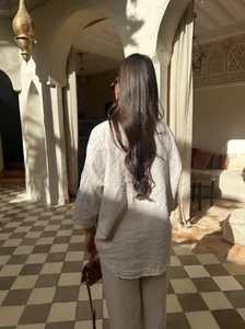 Vue arrière d'un ensemble chemise et pantalon en lin dans un cadre intérieur ensoleillé.