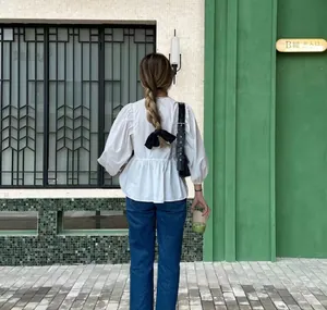 Close-up rear view of a white casual puff sleeve blouse featuring a black bow back detail