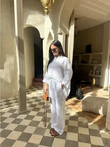 Femme portant un ensemble de détente blanc en coton et lin deux pièces dans un complexe.