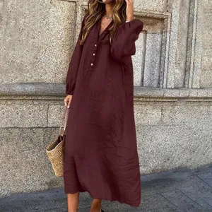 Outdoor street style view of a burgundy long-sleeved cotton linen maxi dress with buttons.