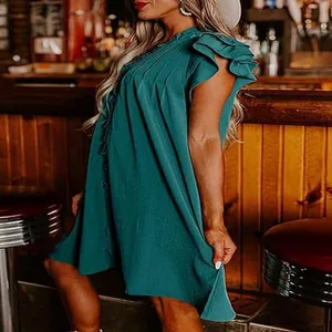 Side view detail of a teal V-neck ruffled sleeve dress in a casual lifestyle setting