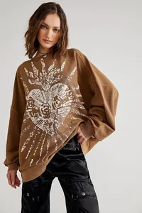 Detail view of an oversized brown sweatshirt with a vintage white heart sunburst graphic.