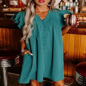 Detailed view of ruffle sleeves and V-neckline on a teal summer dress in a bar setting