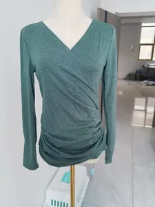 Détail d'un haut vert à manches longues avec col en V et drapé élégant sur un mannequin