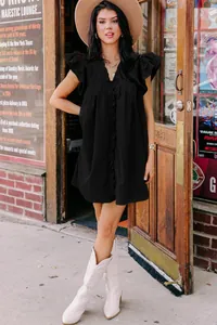 Lifestyle detail of a black V-neck dress with ruffle sleeves and casual relaxed fit