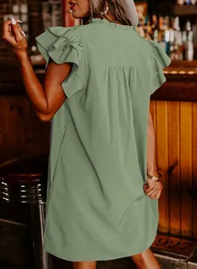Back view detail of a sage green V-neck ruffle sleeve dress in an atmospheric bar setting