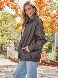 Oversized dark brown faux leather motorcycle jacket for women against autumn leaves