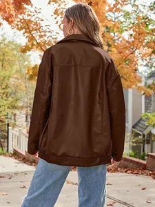 Back view of a stylish oversized brown faux leather biker jacket in an autumn park.